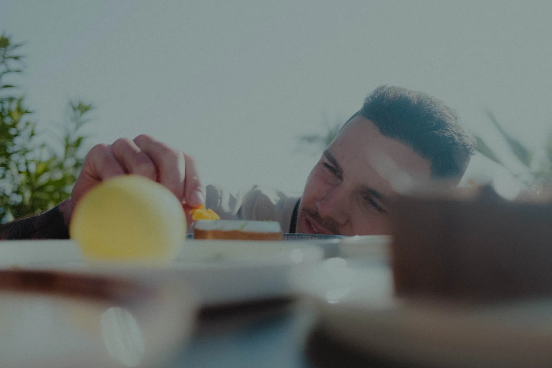 Adrien, chef pâtissier, pose délicatement le trompe-l'œil citron sur l'assiette